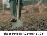Farmer in rubber boots using...