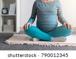 Small photo of Pregnant woman practicing yoga exercise at home. Pregnancy yoga and indoors fitness concept. Ungraded low contrast footage with natural window light.
