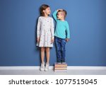 Little girl and boy measuring their height near color wall