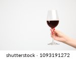 Woman holding glass of red wine on white background