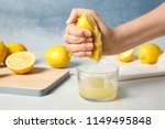 Woman squeezing lemon juice into glass on table