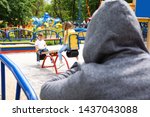 Suspicious adult man spying on kids at playground, space for text. Child in danger