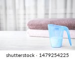 Measuring cup of washing powder on table against blurred background. Space for text