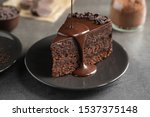 Pouring chocolate sauce onto delicious fresh cake on grey table, closeup