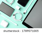 USB charge cables, power adapter and gadgets on light blue background, flat lay. Modern technology