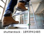 Professional constructor on ladder in old building, closeup