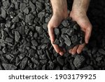 Man holding coal in hands over pile, top view. Space for text