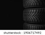 Winter tires on black background, closeup. Space for text