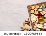 Cheese plate with honey, grapes and nuts on white table, flat lay. Space for text