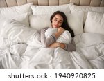 Beautiful young woman wrapped with soft blanket sleeping in bed at home, above view