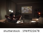 Man watching movie on sofa at night, back view. Space for text