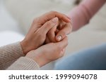 Psychotherapist holding patient's hand indoors, closeup view