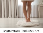 Woman standing on faux fur rug at home, closeup. Space for text