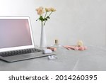 Modern laptop, flowers and makeup products on grey marble table. Space for design