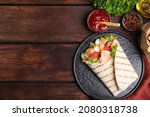 Delicious shawarma with chicken meat and vegetables  served on wooden table, flat lay. Space for text