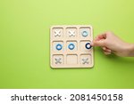 Small photo of Woman playing tic tac toe game on light green background, top view