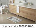 Small photo of Soft bath mat and slippers on floor in bathroom