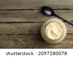 Small photo of Jar of delicious mayonnaise and spoon on wooden table, flat lay. Space for text