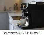 Small photo of Modern electric espresso machine with cup of coffee on white marble countertop in kitchen