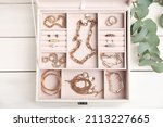 Jewelry box with stylish golden bijouterie on white wooden table, flat lay