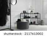 Shelving unit with stylish women's shoes, clothes and accessories in dressing room