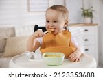 Small photo of Cute little baby wearing bib while eating at home