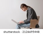 Woman with bad posture using laptop while sitting on chair against light grey background, space for text