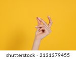 Woman snapping fingers on yellow background, closeup of hand