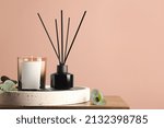 Composition with aromatic reed air freshener on wooden table near pink wall, space for text