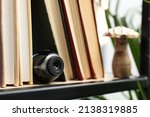 Camera hidden between books on wooden shelf indoors, closeup. Space for text