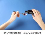 Woman pouring cough syrup into spoon on blue background, closeup