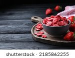 Freeze dried and fresh strawberries on black wooden table. Space for text