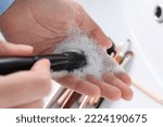 Woman washing makeup brush with soap, closeup