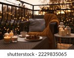 Small photo of Beautiful view of garden furniture with pillow, soft blanket and burning candles at balcony