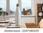White thermos bottle at wooden table indoors