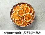 Bowl of dry orange slices on light table, top view