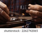 Professional jeweler working with gemstone at wooden table, closeup