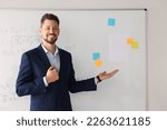Happy teacher explaining mathematics at whiteboard in classroom