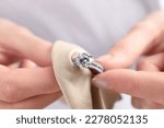 Small photo of Jeweler cleaning diamond ring with microfiber cloth, closeup