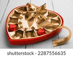 Partially empty box of chocolate candies on white wooden table, closeup