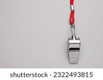 Small photo of One metal whistle with red cord on light grey background, top view. Space for text