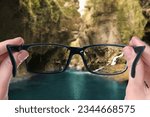 Small photo of Vision correction. Woman looking through glasses and seeing landscape clearer