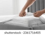 Woman covering mattress with protector indoors, closeup
