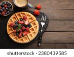 Tasty Belgian waffle with fresh berries served on wooden table, flat lay. Space for text