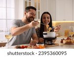 Affectionate couple enjoying cheese fondue during romantic date in kitchen