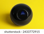 Small photo of Magic eight ball with prediction Answer Unclear Ask Later on yellow background