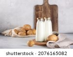 Small photo of Vegan plant based milk in two bottles. Alternative potato milk and potato tubers on gray table
