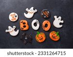 Small photo of Halloween gingerbread cookies: text BOO, bats, pumpkins and ghosts on dark stone background. Halloween concept