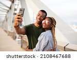 Small photo of Happy smilng couple taking selfie with phone outdoors. Boyfriend and girlfriend having fun outdoors