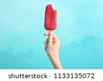 Woman holding delicious strawberry popsicle on color background